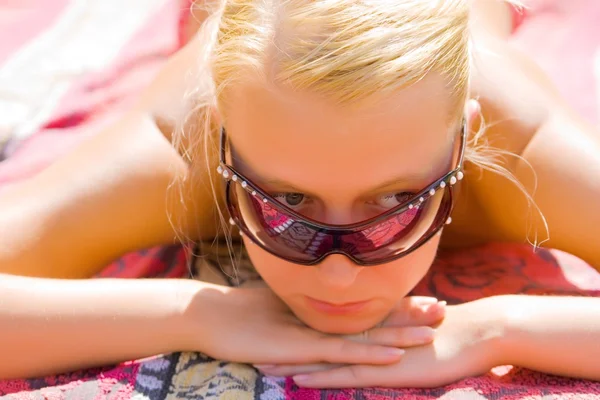 Девушка в солнечных очках принимает солнечные ванны — стоковое фото