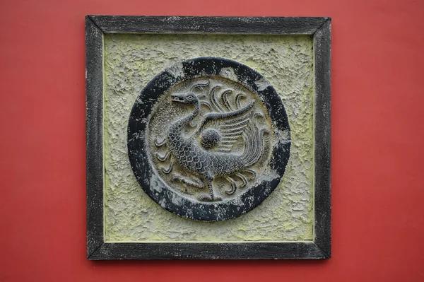 Bronzen phoenix sculptuur op een rode muur — Stockfoto