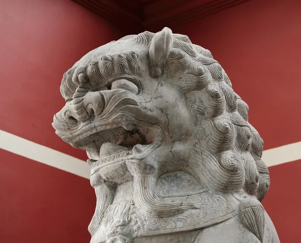 Каменная статуя льва перед красной стеной — стоковое фото