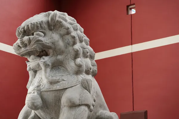 Lew kamień statua przed czerwone ściany — Zdjęcie stockowe