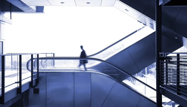 Homem de negócios em movimento na escada rolante — Fotografia de Stock