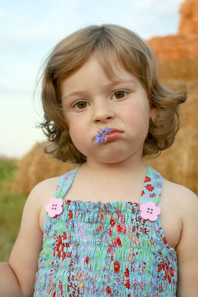 The sad girl with a cornflower in lips — Stock Photo, Image