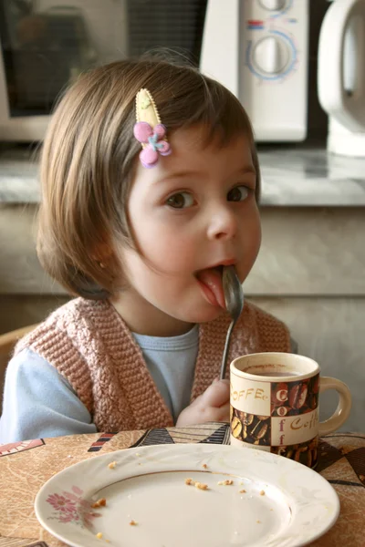 The girl licks a spoon — Stock Photo, Image