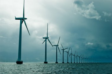 Windmills in a row on cloudy weather clipart