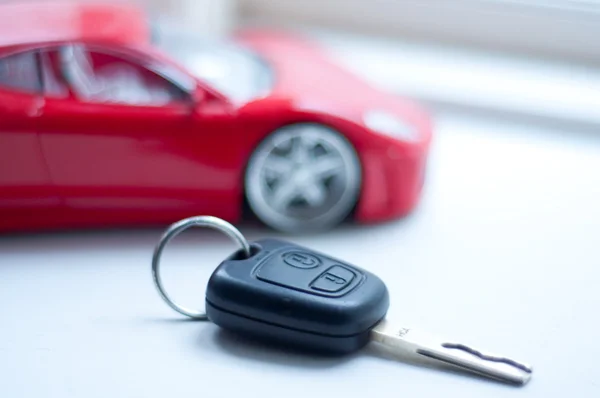 Автомобільний ключ біля маленької віддаленої червоної суперкарти — стокове фото