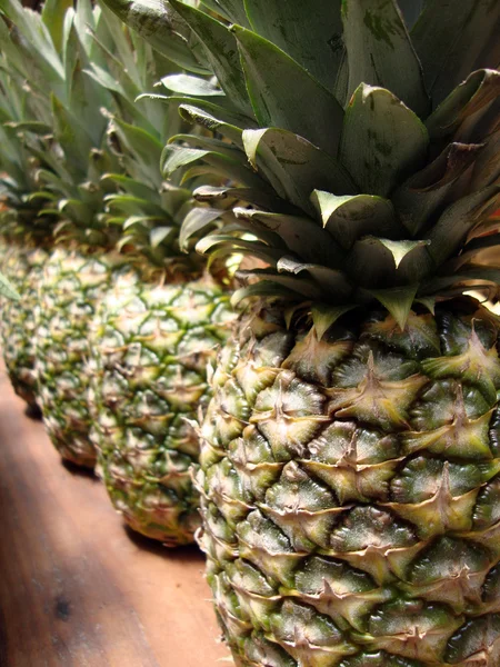 Rij van ananas op houten tafel — Stockfoto