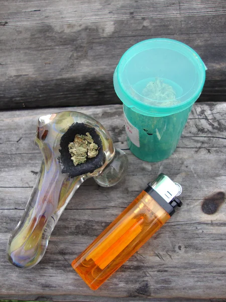 Glas Marihuana, Pfeife und Feuerzeug auf einem Brunnen sitzend — Stockfoto