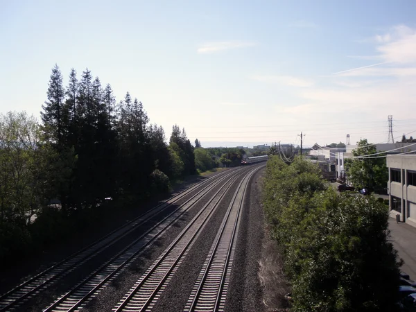 Vía de tren de cuatro carriles con tren a distancia rodando aunque — Foto de Stock