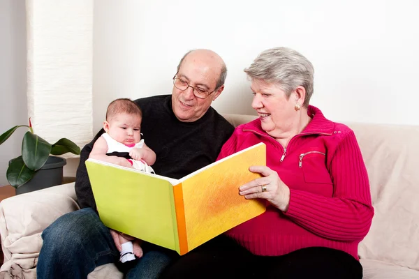 Dziadkowie czytanie książki dziewczynka. — Zdjęcie stockowe