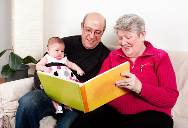 Бабушка и дедушка читают книгу малышке . — стоковое фото
