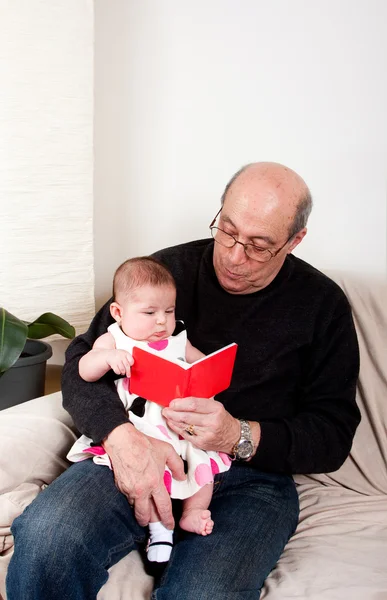 Opa liest Baby-Mädchen rotes Buch vor — Stockfoto