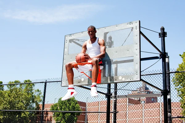 Jogador de basquete sentado em aro — Fotografia de Stock
