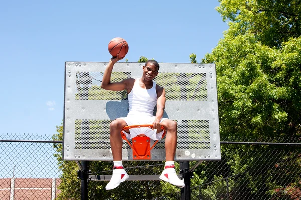Champion basketball player sits in hoop — Stock Photo, Image