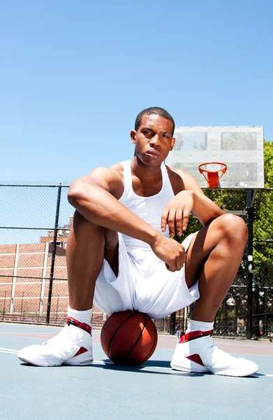 Basketball player sitting on ball — Stock Photo, Image