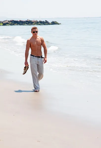 Hombre guapo caminando en la playa — Foto de Stock