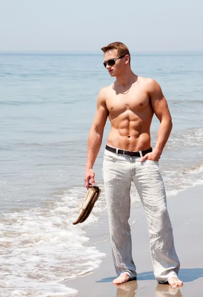 Yakışıklı bir adam sahilde duran — Stok fotoğraf