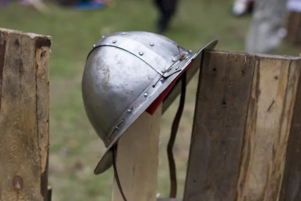 Old knight helmet on fence with some knights in background