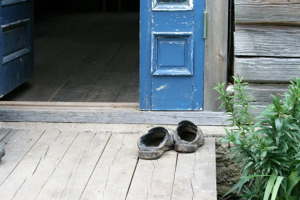 Zapatos viejos en la puerta de madera — Foto de Stock