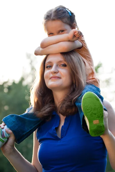 Holčička na ramenou matky — Stock fotografie