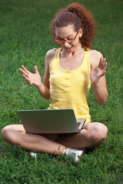 Unga kvinnor med laptop på en äng — Stockfoto