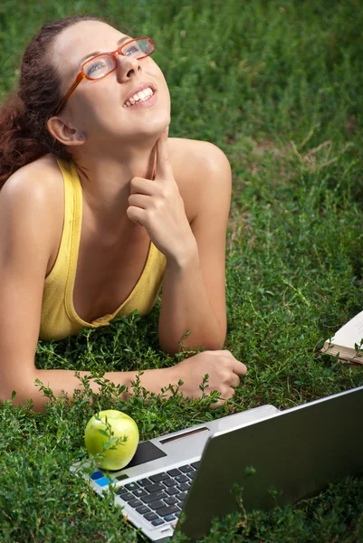 Unga kvinnor med laptop på en äng — Stockfoto