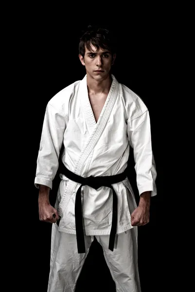 Kontrast karate mladý bojovník na černém pozadí — Stock fotografie