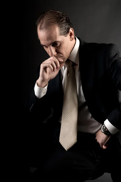 Homem de negócios adulto pensamento sério sentado no fundo escuro — Fotografia de Stock