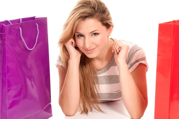 Young woman with shopping bags lying on floor on white background — Stock Photo, Image