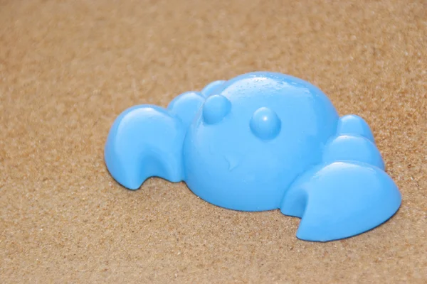 Синий игрушечный краб на песчаном пляже — стоковое фото