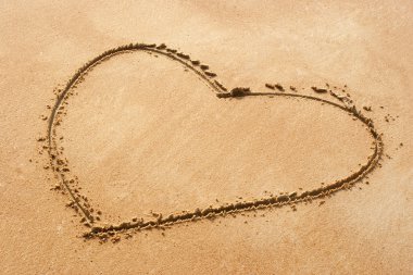 Heart shape symbol on sandy beach clipart