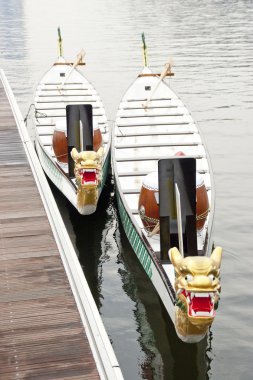 Two dragon boats tied up at jetty clipart