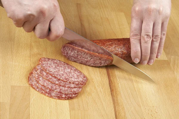 Mulher cortando salsicha por faca — Fotografia de Stock