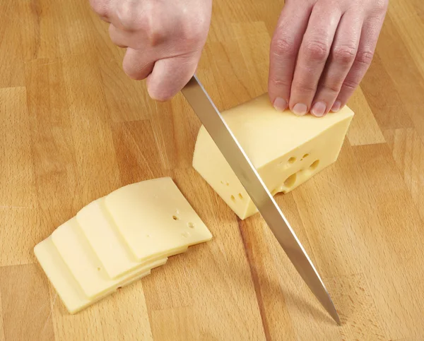 Woman cutting cheese by knife — Stock Photo, Image