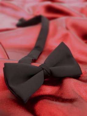 Black bow tie against red satin backgrou clipart