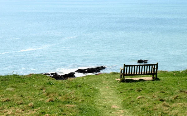 Lonely bench on coast hillside against a — Stock Photo, Image