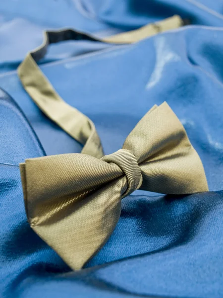 Gold bow tie against blue satin — Stock Photo, Image