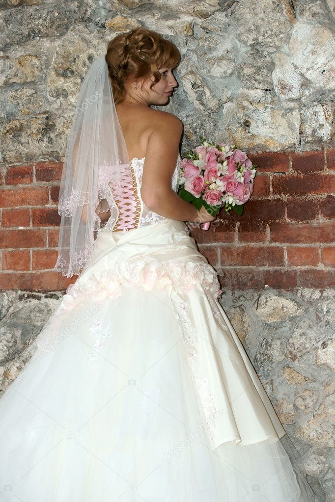The bride with a bouquet at a wall
