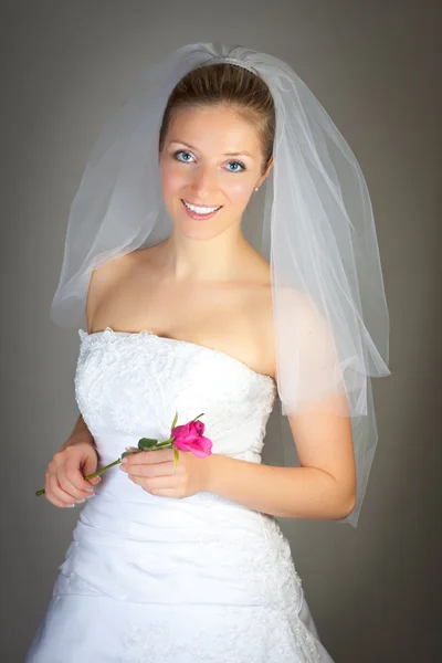 Brud poserar i brudklänning och ros — Stockfoto