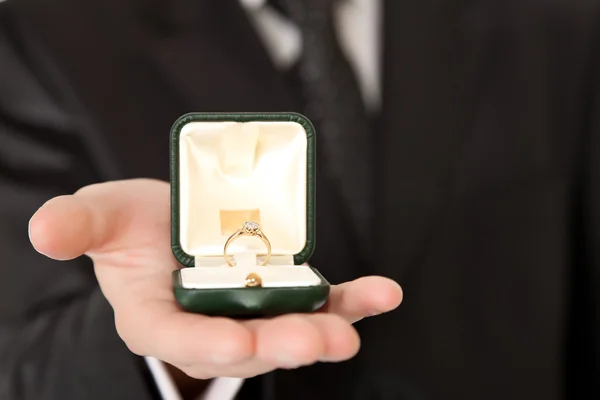 Homem de terno segurando anel de noivado no fundo isolado branco — Fotografia de Stock