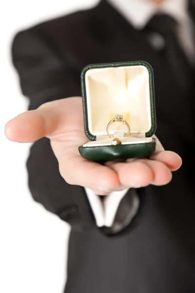 Mann im Anzug hält Verlobungsring auf weißem Hintergrund — Stockfoto