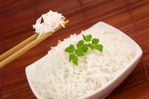 stock image Closeup of rice on chopsticks and a bowl on mat