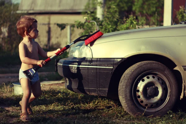 लाल ब्रशसह लहान मुलगा कार धुतला स्टॉक इमेज