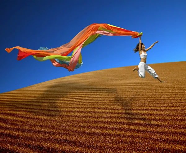 Regenbogenfrau springt über die Dünen — Stockfoto