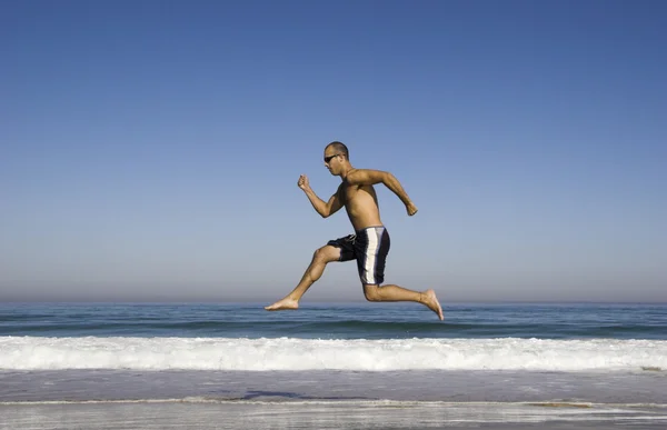 男性を実行していると、ビーチ上にジャンプ — ストック写真