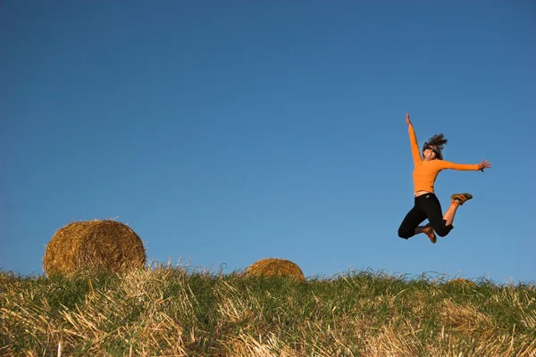 Donna che salta in un campo di balle di fieno — Foto Stock