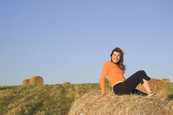 Красивая женщина в поле с тюками сена — стоковое фото