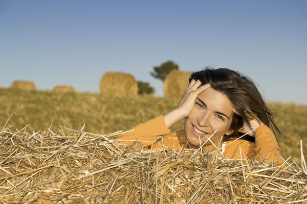 Mulher bonita em um campo com fardos de feno — Fotografia de Stock