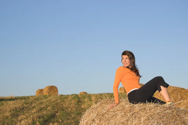 Hermosa mujer en un campo con fardos de heno — Foto de Stock