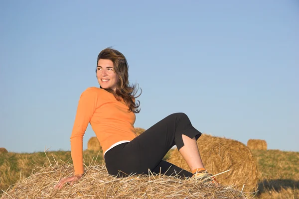 Bella donna in un campo con balle di fieno — Foto Stock