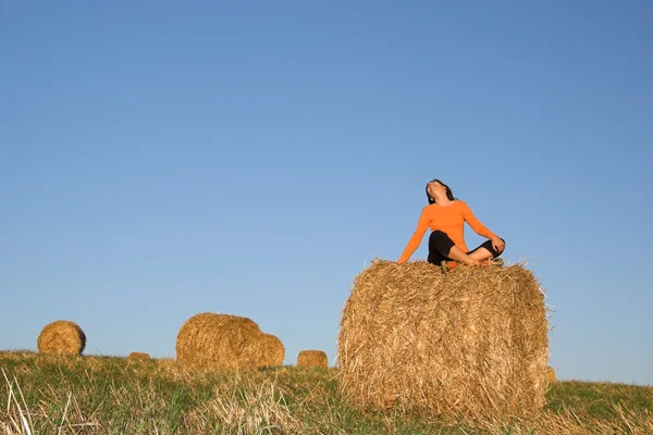 Beautiful woman seated in hay bale — Stock Photo, Image